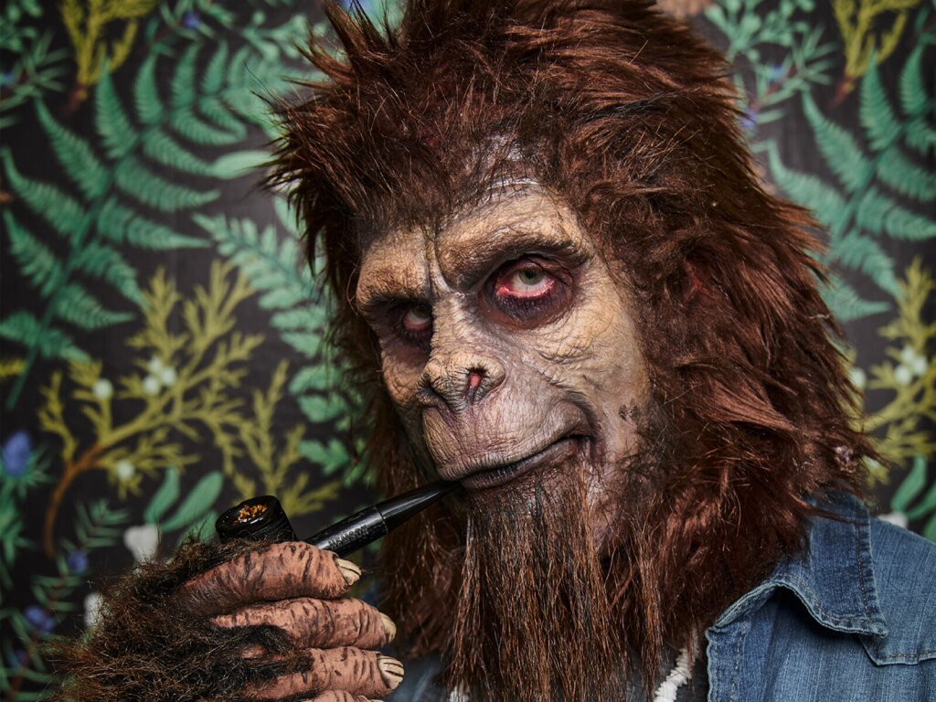 A portrait of a sasquatch smoking a pipe with a floral background.