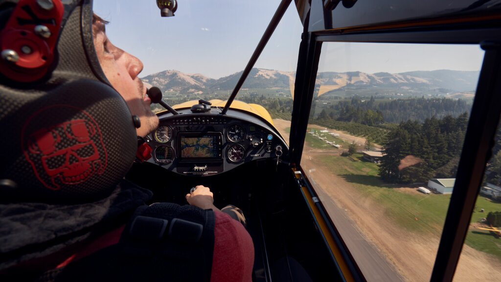 A photo of a pilot looking upward shot from inside a small plane.