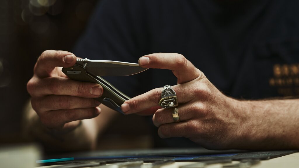 Male hands holding a partially folded knife.