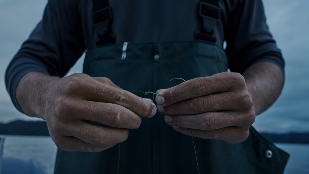 Close-up photo of a man tying a fish hook.