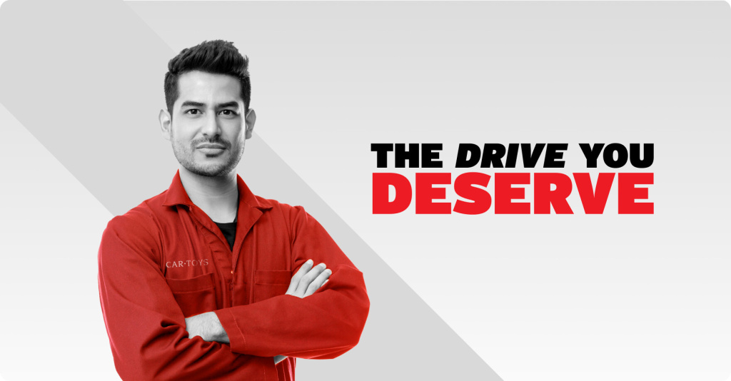 Car Toys employee standing proudly with his arms crossed with the text "The Drive You Deserve" is seen to the right.