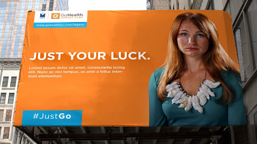 A large billboard in a city for Legacy GoHealth featuring a woman wearing a rabbit's foot necklace that reads: "Just Your Luck.".