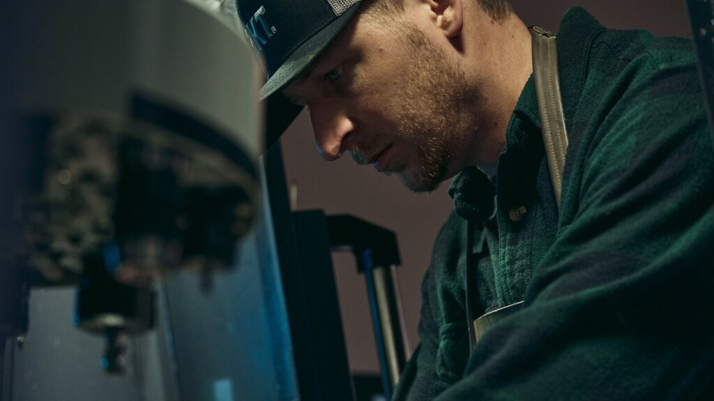 A photo of knife designer, TJ Schwarz working at a machine.